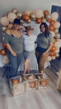 three women posing for a photo in front of balloons